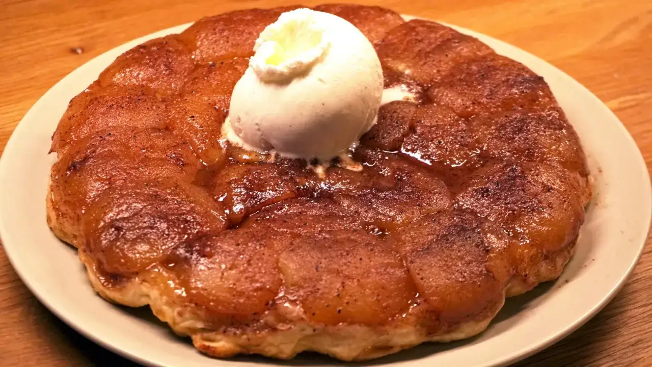En gyllene tarte tatin med en kula vaniljglass som smälter över de karamelliserade äpplena.