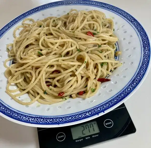 Person wiegt rohe Spaghetti auf einer digitalen K&uuml;chenwaage