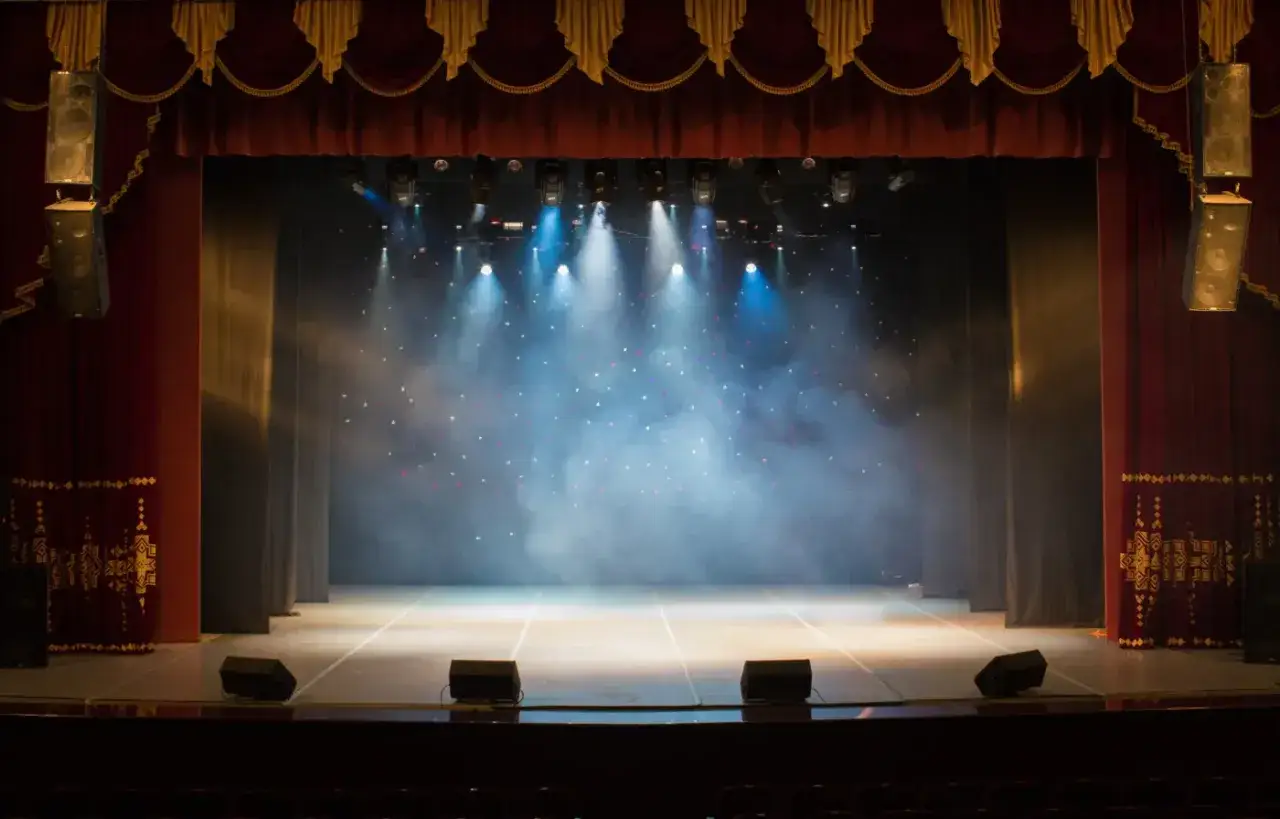 Pusta scena teatralna w dymie i świetle, gotowa na spektakl. Sprawdź tr warszawa repertuar!