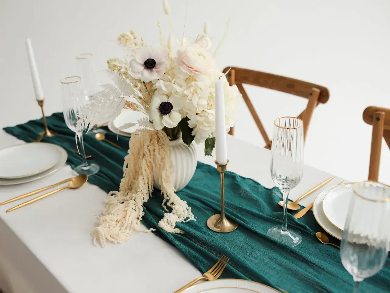 Une table dress&eacute;e pour un mariage vert d'eau, avec des fleurs blanches, des bougies et de la vaisselle dor&eacute;e.