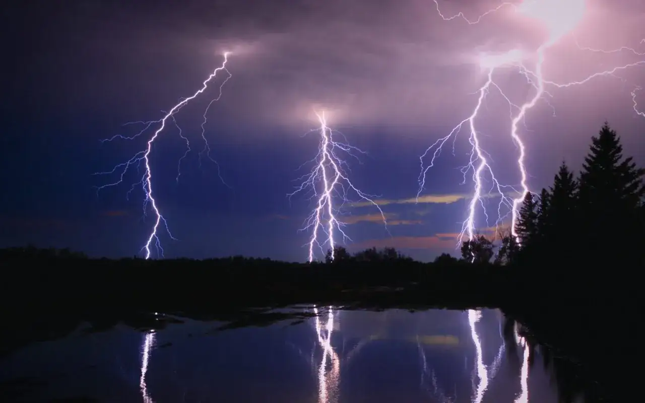 &Eacute;clairs z&eacute;brant un ciel nocturne, refl&eacute;t&eacute;s dans l'eau calme. Une photo d'orage spectaculaire.
