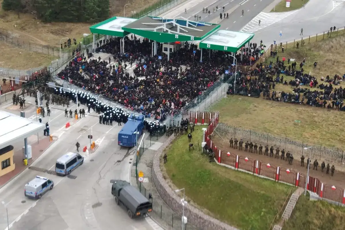 Tłum ludzi przy przejściach granicznych z Białorusią, otoczony przez policję i wojsko.