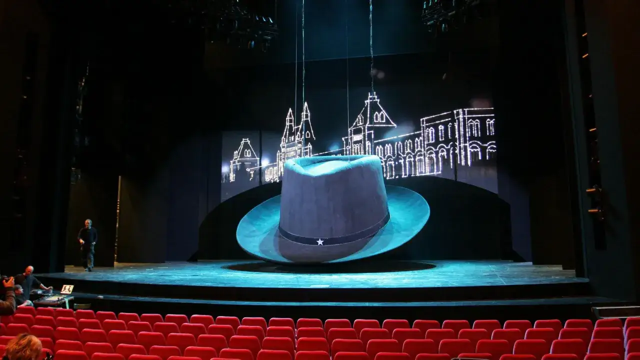 Bühne mit riesigem Hut und Stadtkulisse, bereit für Musicals in Deutschland.