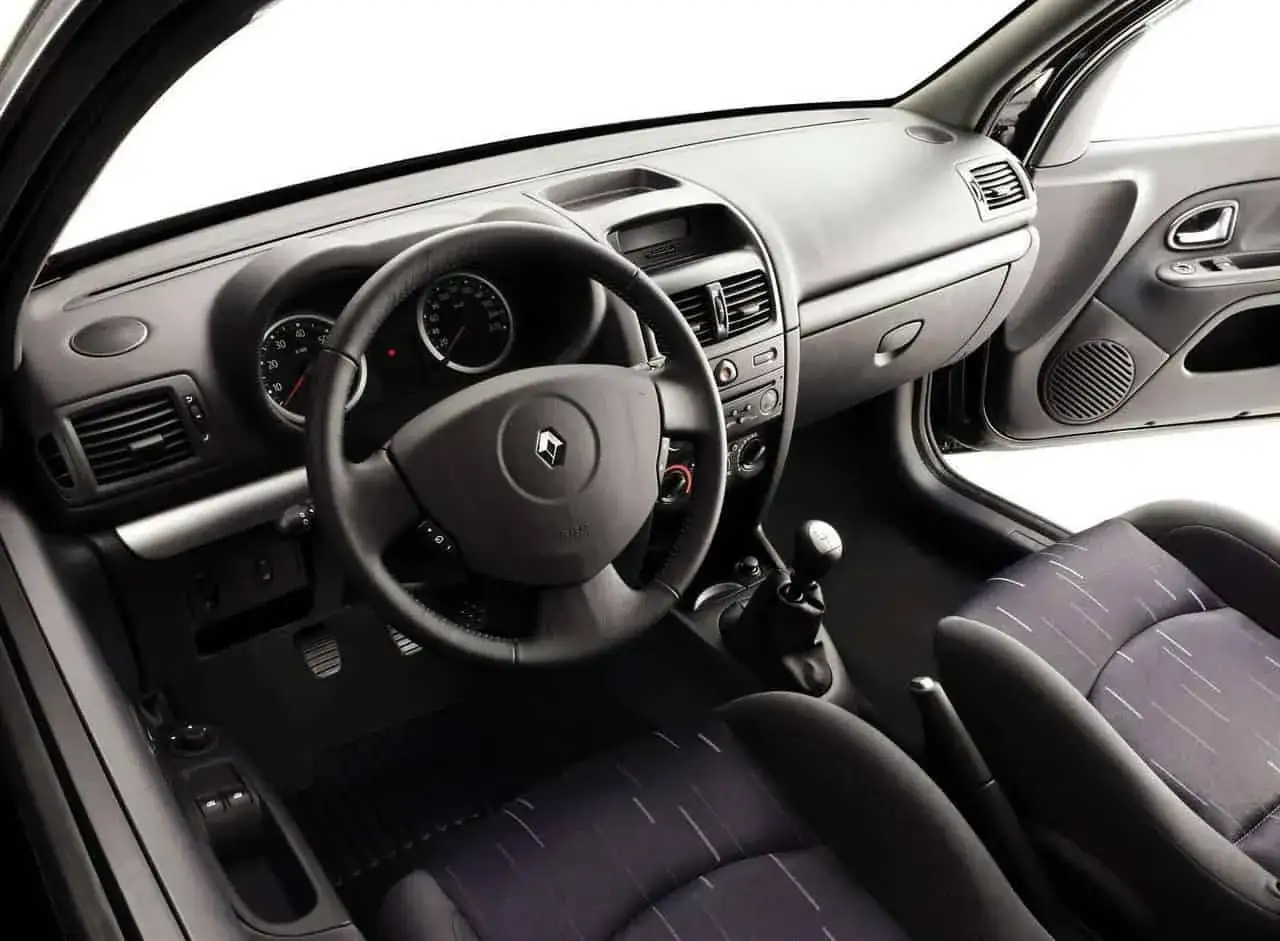 Wnętrze Renault Clio 2: kierownica, deska rozdzielcza z zegarami, dźwignia zmiany biegów i fotele.