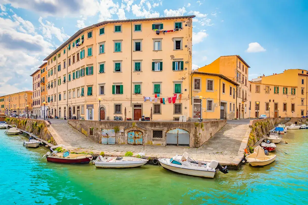 Canali e palazzi colorati a Livorno, un'idea per cosa vedere a Livorno in un giorno. Barche ormeggiate nell'acqua verde.