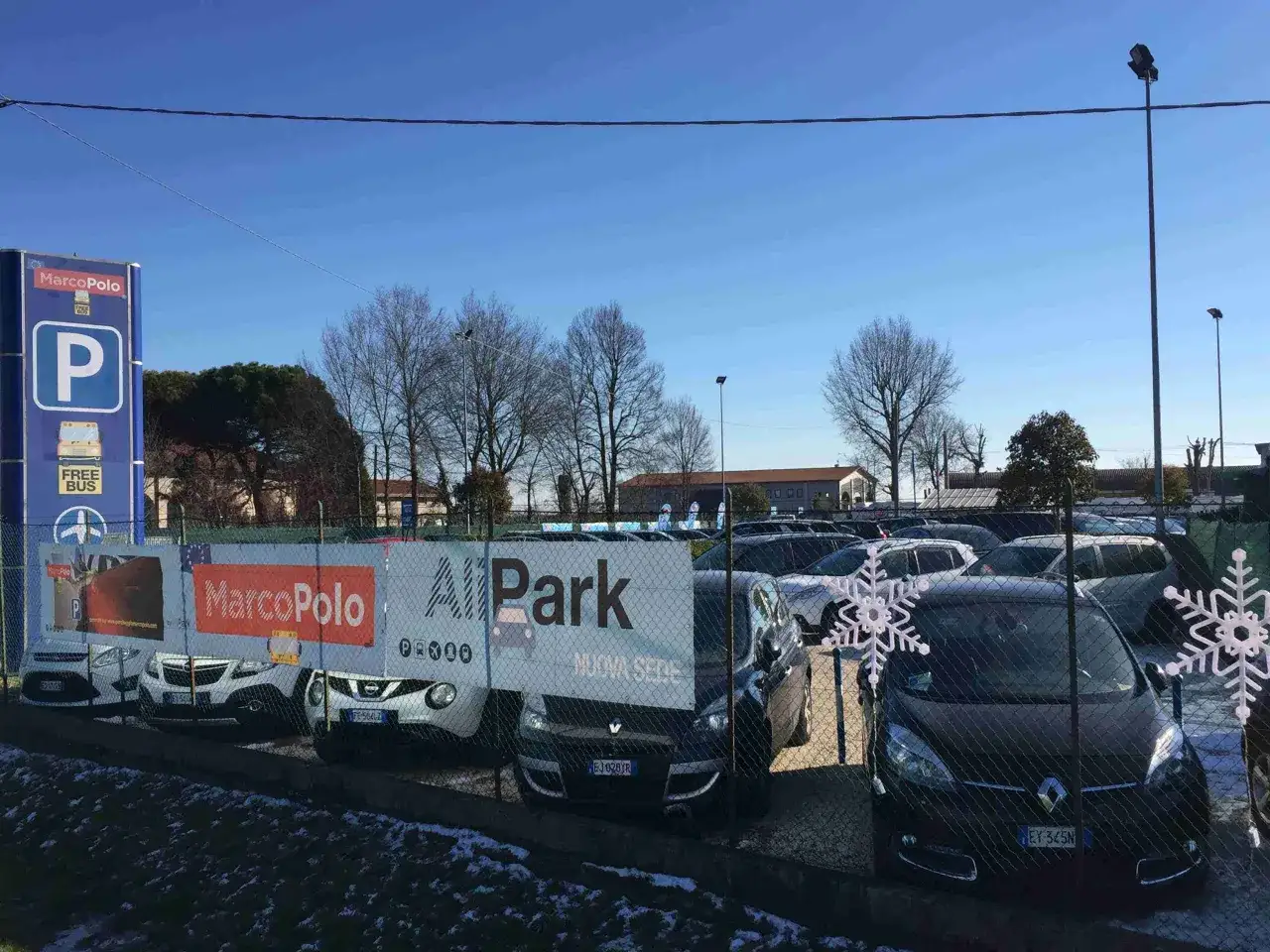 Parcheggio a Piazzale Roma, Venezia. Auto parcheggiate dietro una rete con decorazioni a fiocco di neve.