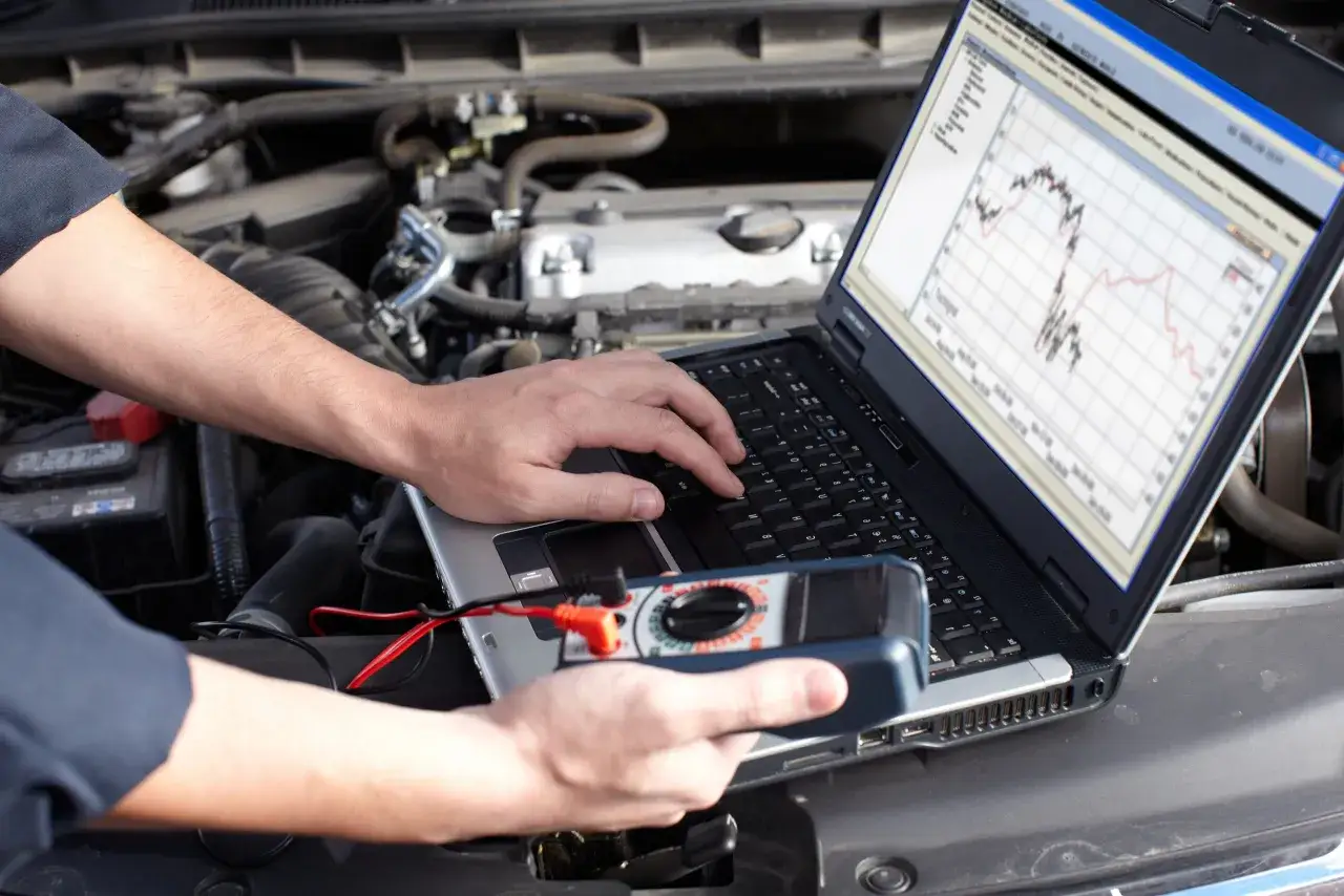 Un m&eacute;canicien utilise un ordinateur portable et un multim&egrave;tre pour diagnostiquer un probl&egrave;me moteur. Peut-on rouler avec un calculateur HS ? Ce diagnostic est essentiel.