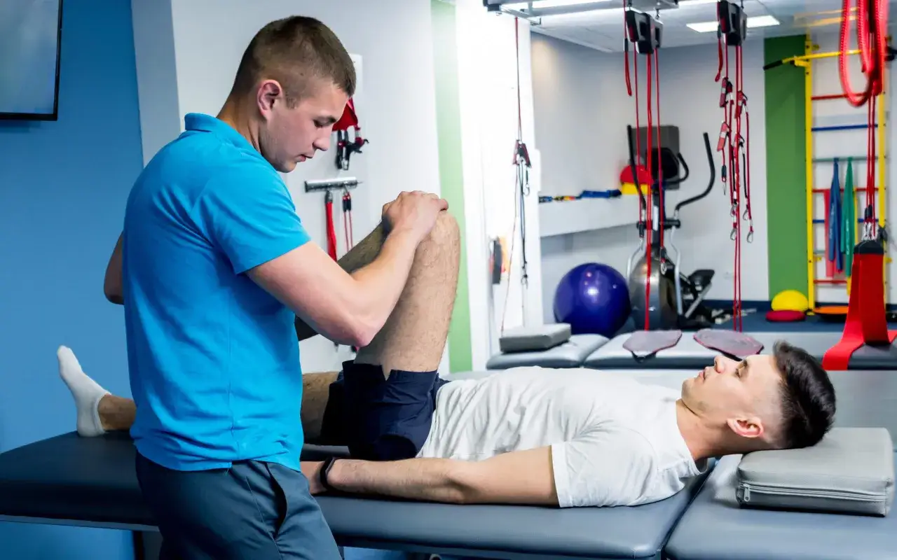 Fizjoterapeuta wykonuje ćwiczenia podczas sesji fizjoterapii ortopedycznej, pomagając pacjentowi w rehabilitacji.