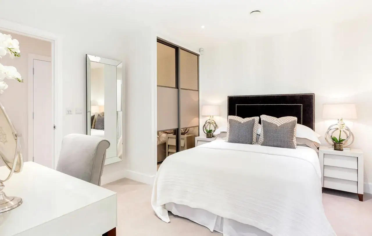 Elegante camera da letto senza finestra, con letto king-size, specchio a figura intera e un angolo toeletta.