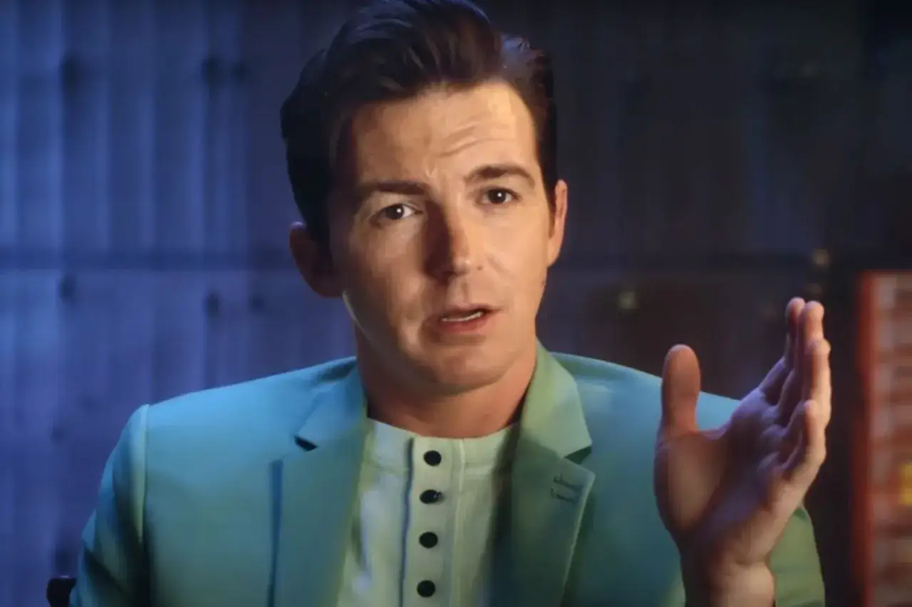 Drake Bell w turkusowej marynarce, opowiadający o swoich filmach, serialach i programach.