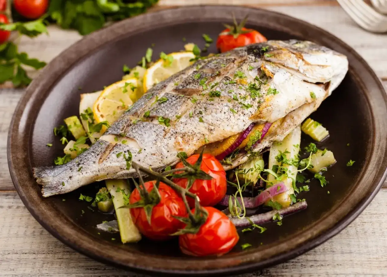 Poisson entier grillé, garni de citron et de tomates cerises, prêt à être dégusté. Une truite au barbecue savoureuse.