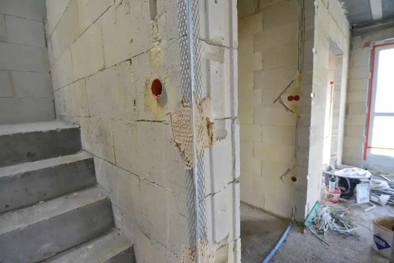 Budowa trwa, widać schody betonowe i ściany z bloczków. Zastanawiasz się, co najpierw tynki czy wylewki? Instalacje elektryczne czekają na wykończenie.
