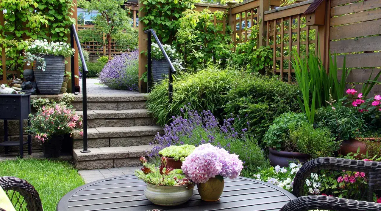 Un jardín exuberante con escalones de piedra, lavanda y macetas que muestran cómo mezclar plantas en la misma maceta.