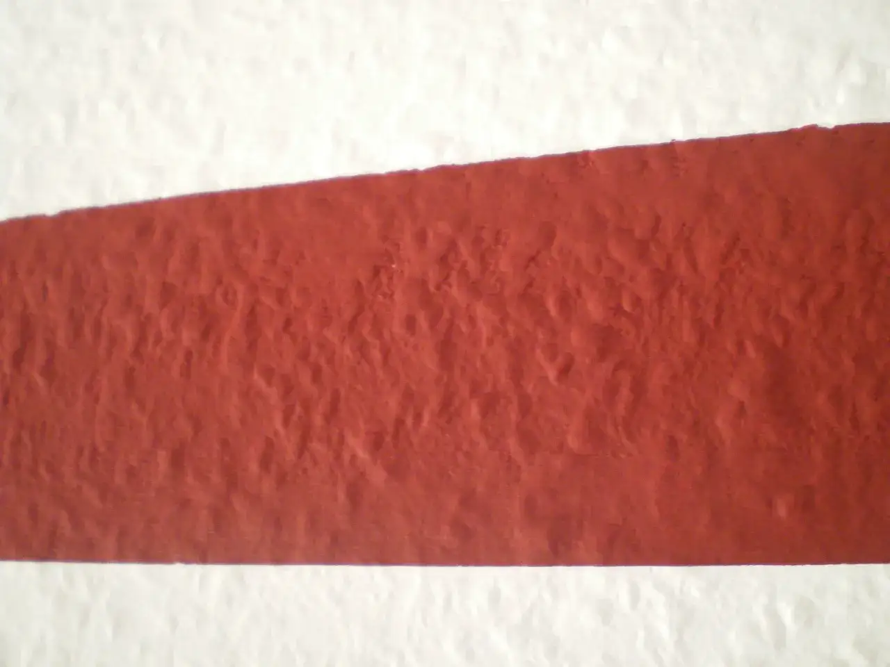 Eine Wand wird mit einem roten Streifen und einem sauberen Rand gestrichen.