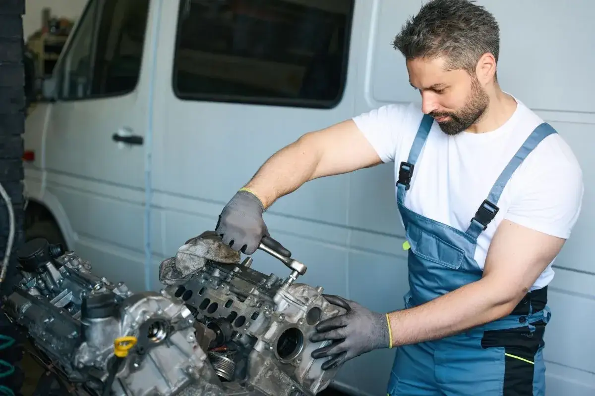 Mechanik w warsztacie dokręca śruby pokrywy zaworów silnika, dbając o prawidłową kolejność.