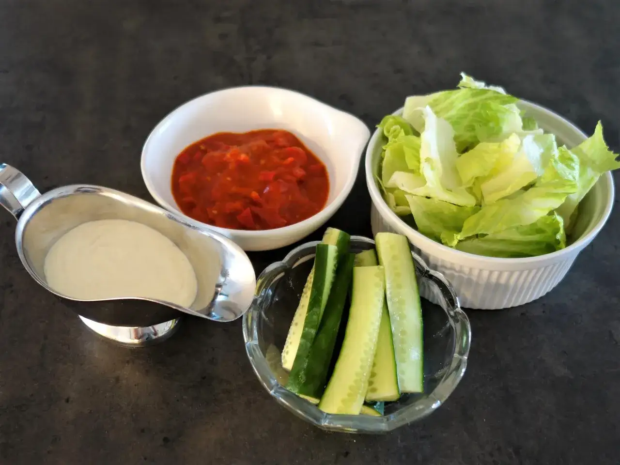 En sk&aring;l med vit kebabs&aring;s, en sk&aring;l med tomats&aring;s, en sk&aring;l med sallad och en sk&aring;l med gurkstavar. Perfekt f&ouml;r ett gott kebabs&aring;s recept!