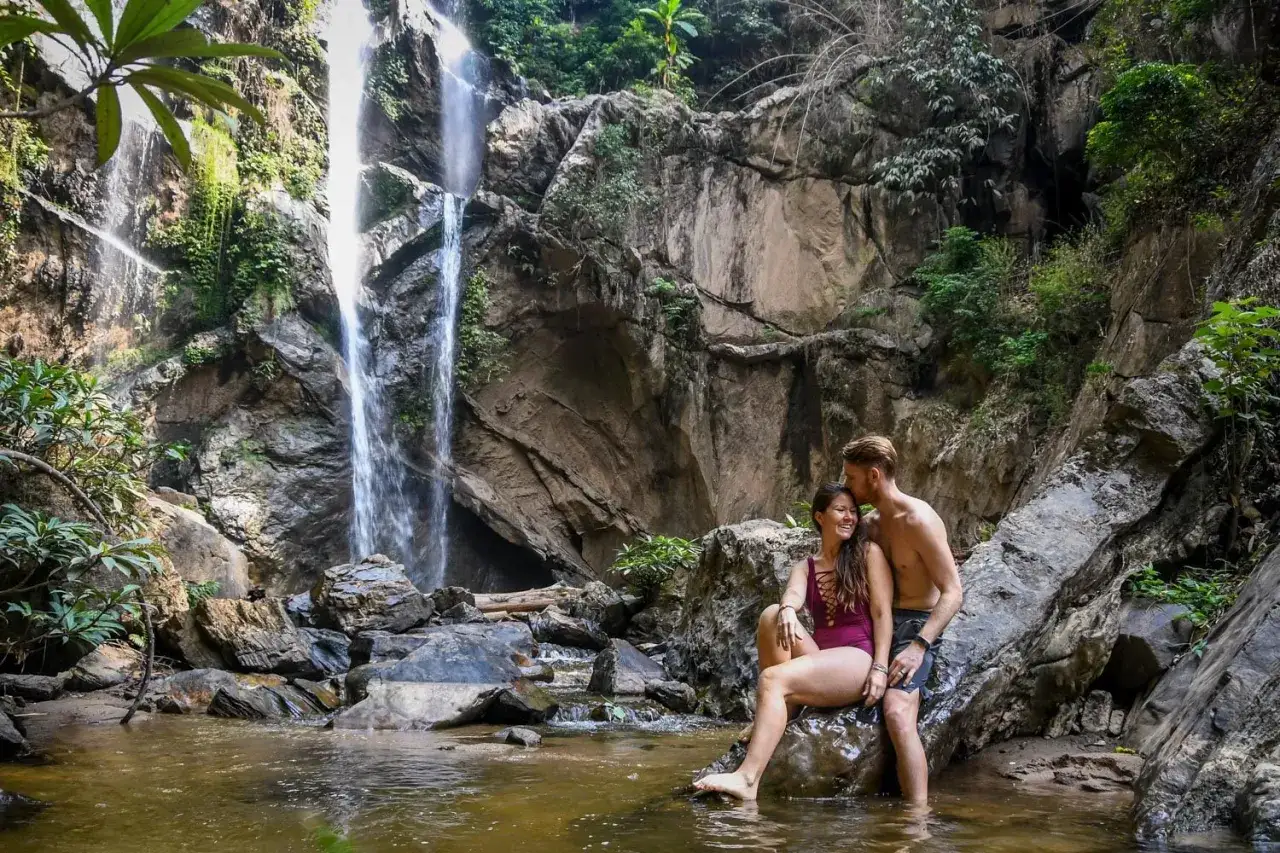 Para zobaczyć w Chiang Mai: para odpoczywa przy wodospadzie Mae Sa, otoczona bujną zielenią i skalistymi klifami.