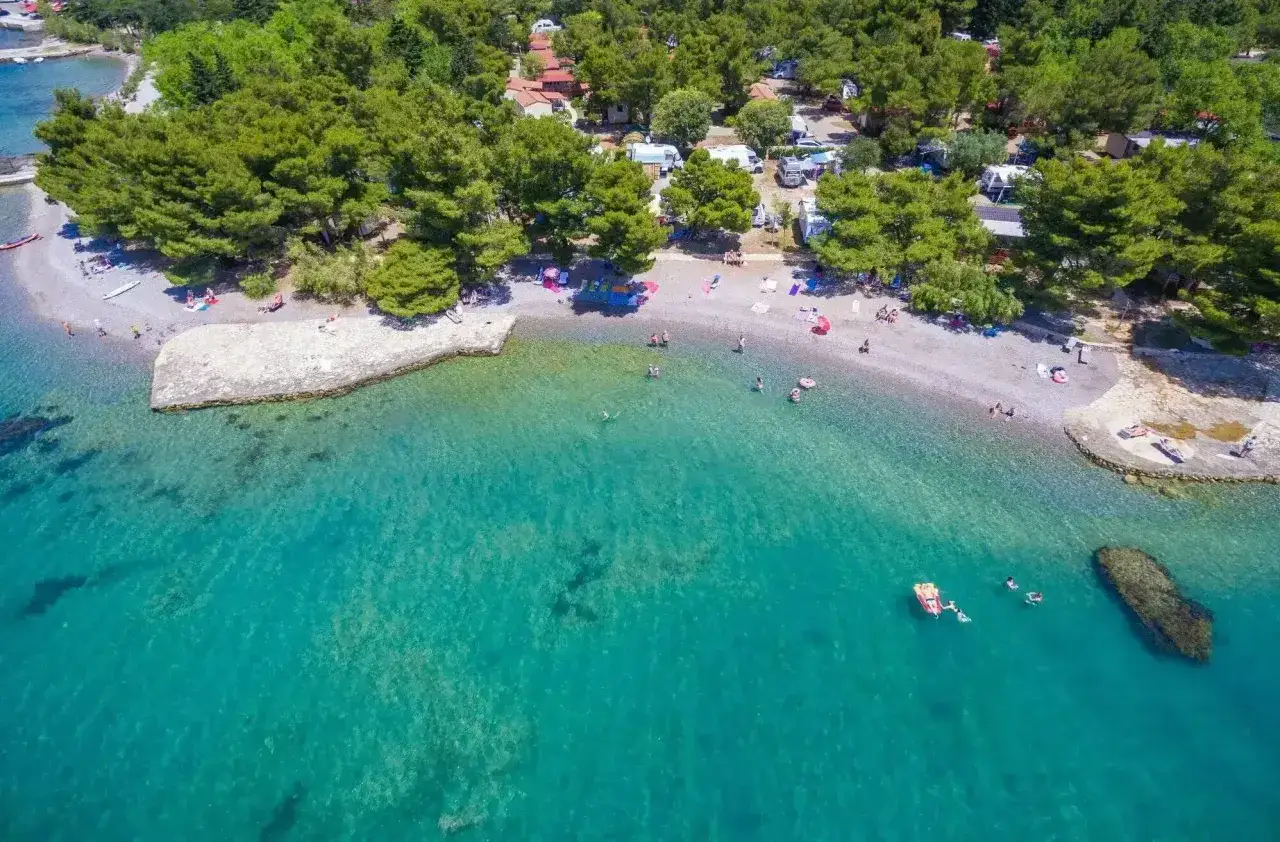 Malownicza plaża z turkusową wodą, drzewami i kamperami. Idealne miejsce na wakacje, camping Paklenica.