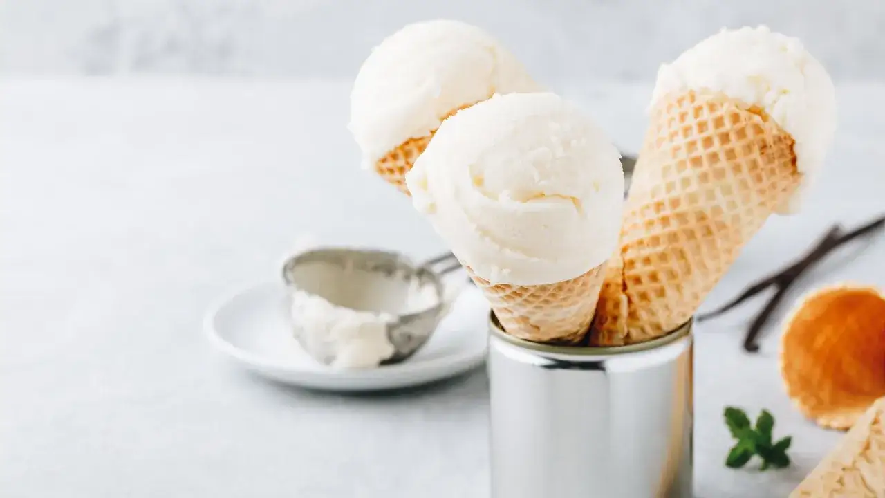 Cremiges griechischer joghurt eis ohne eismaschine in Waffelh&ouml;rnchen. Ein Eisl&ouml;ffel liegt daneben.