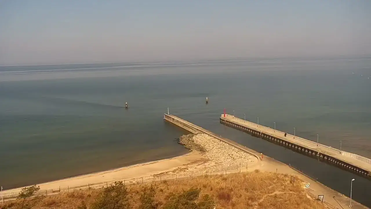 Widok na spokojne morze, falochrony i latarnie morskie. Idealne miejsce na spacer i podziwianie krajobrazów, czyli rowy co warto zobaczyć.