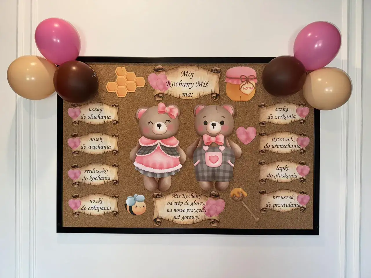 Tablica z okazji dnia misia: dwa misie, serduszka, plastry miodu i balony. Opisuje, co 