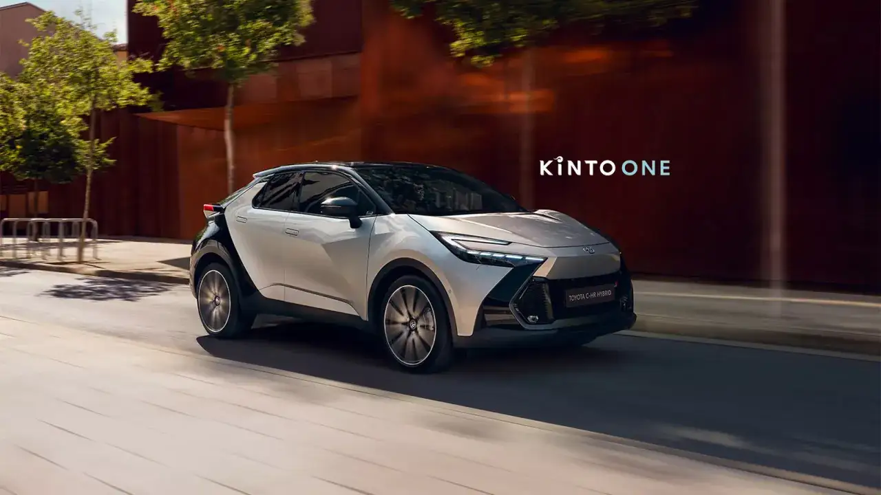 Nowy Toyota C-HR Hybrid w ruchu miejskim, z logo KINTO ONE.