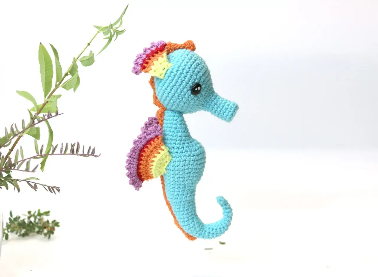 Caballito de mar amigurumi patron gratis. Un tierno caballito de mar tejido a crochet, con aletas arco&iacute;ris y cuerpo azul.