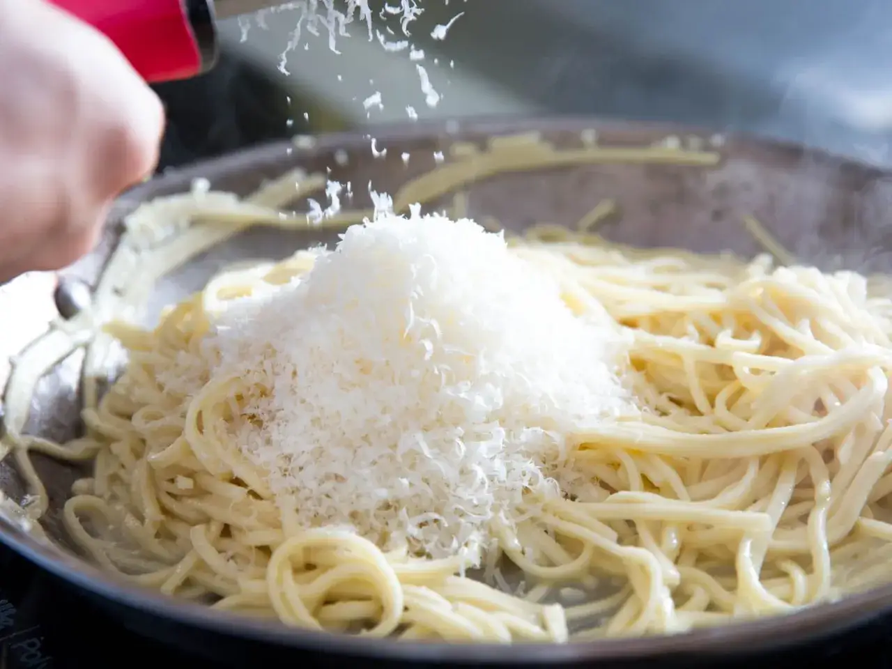 Na gorący makaron sypie się obficie parmezan starty.