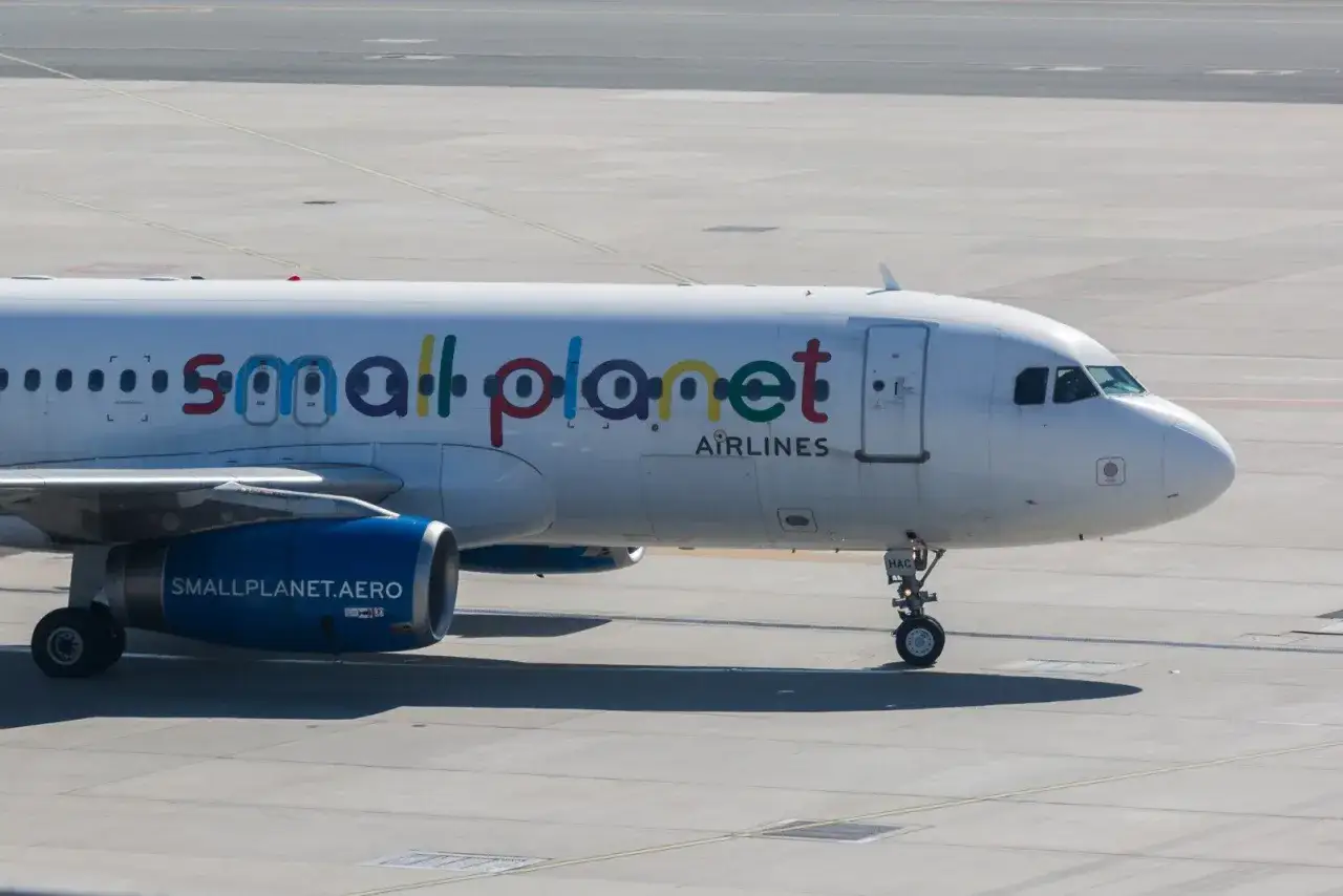 Samolot linii Small Planet Airlines na płycie lotniska. Kolorowe litery nazwy przewoźnika tworzą tęczowy napis.
