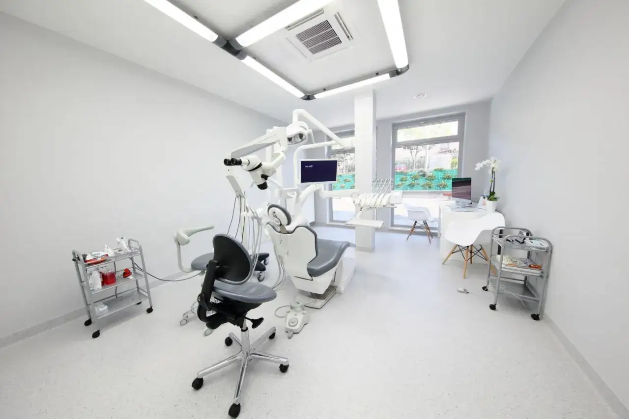 Nowoczesny gabinet stomatologiczny z fotelem, mikroskopem i sprzętem.
