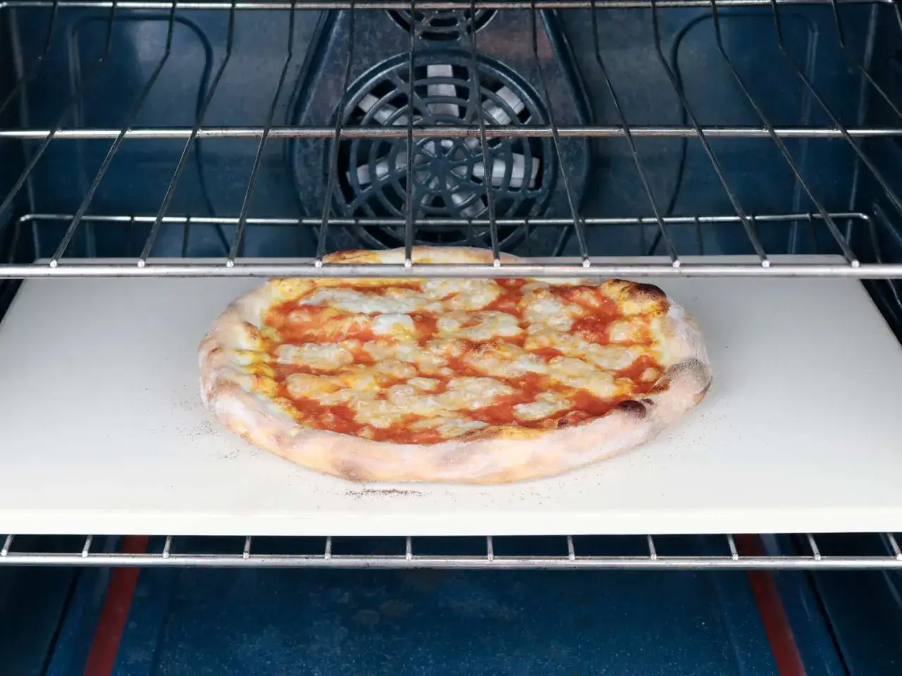 Jedna pizza na kamieniu w piekarniku, gotowa do pieczenia.