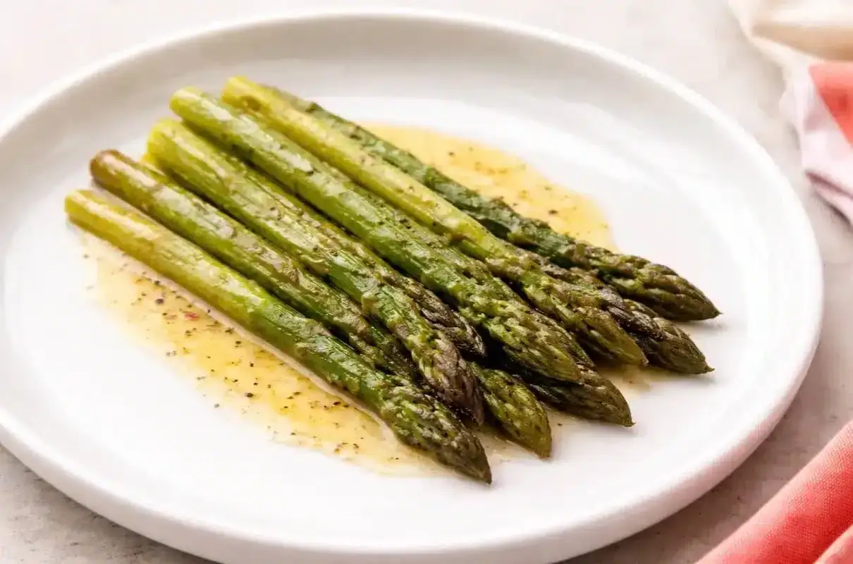 Asparagi verdi cotti e conditi con una salsa dorata, pronti per essere gustati. Ecco come cucinare gli asparagi per un contorno perfetto.