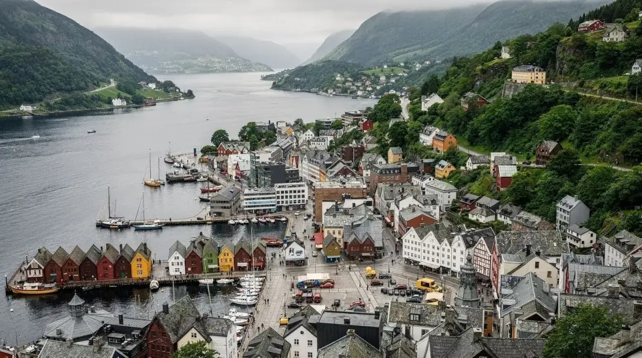 Il porto di Bergen, con le sue case colorate affacciate sull'acqua e le colline verdi sullo sfondo, evoca un'atmosfera di storia e bellezza naturale.
