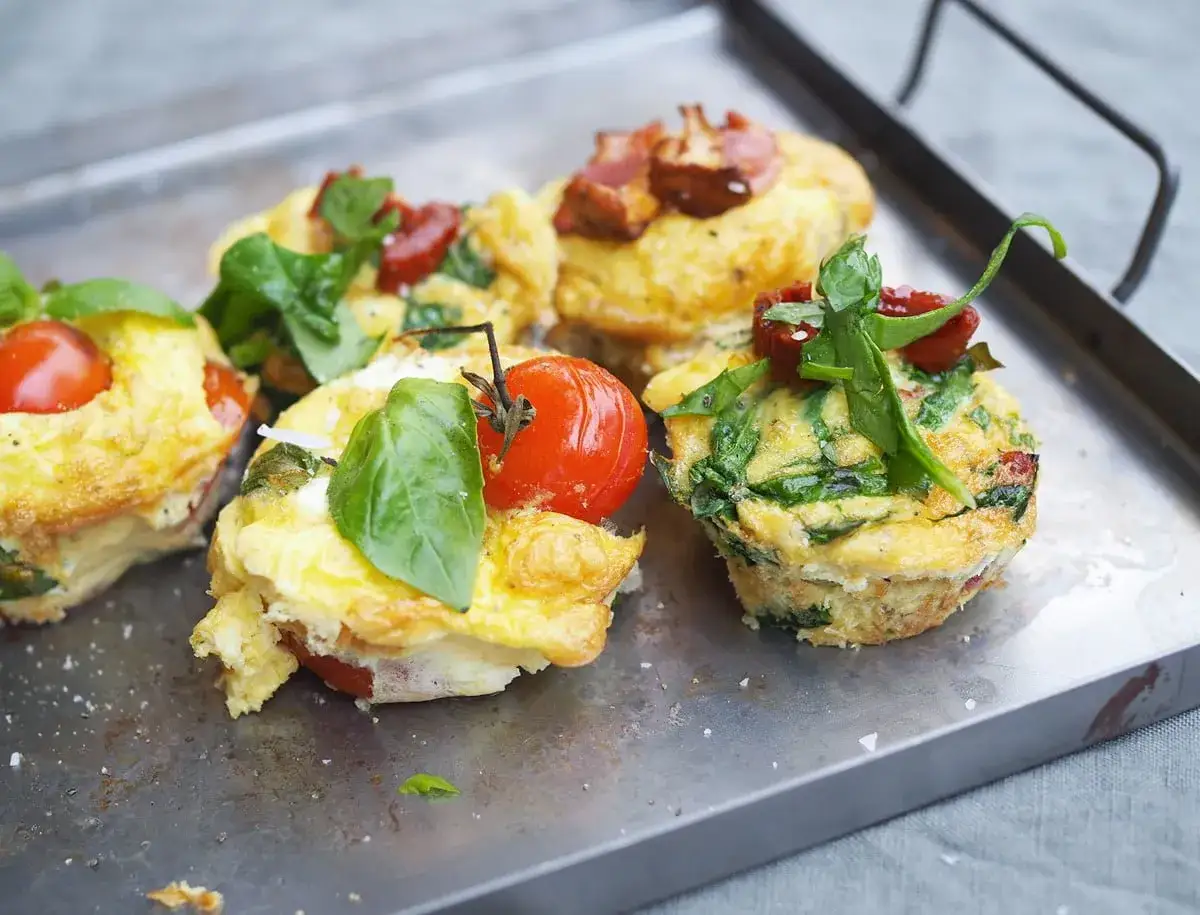 Matiga muffins med &auml;gg, spenat och k&ouml;rsb&auml;rstomater, toppade med f&auml;rsk basilika. Perfekta f&ouml;r en m&auml;ttande frukost eller lunch.