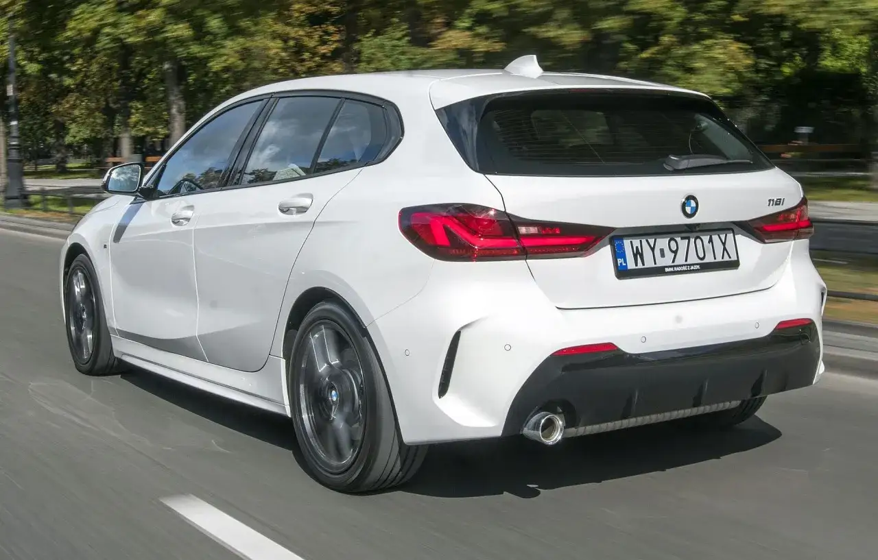 Białe BMW Serii 1 (F40) w ruchu ulicznym, widok z tyłu.