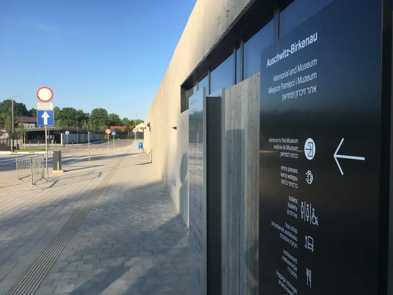 Tablica informacyjna przy Muzeum Auschwitz-Birkenau. Widać napisy po polsku, angielsku i hebrajsku, w tym 