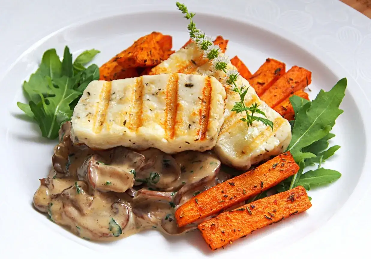 Grillowany halloumi z kremowym sosem grzybowym, pieczonymi batatami i rukolą. Pyszne danie, które zachwyci każdego smakosza.
