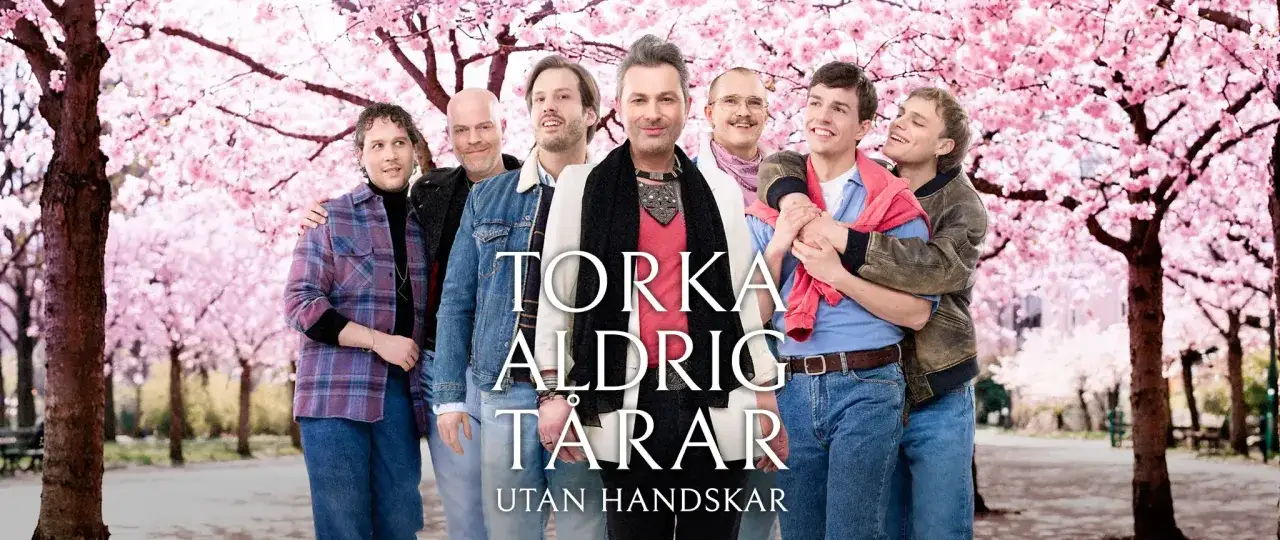 Sju m&auml;n poserar under blommande k&ouml;rsb&auml;rstr&auml;d. Texten 