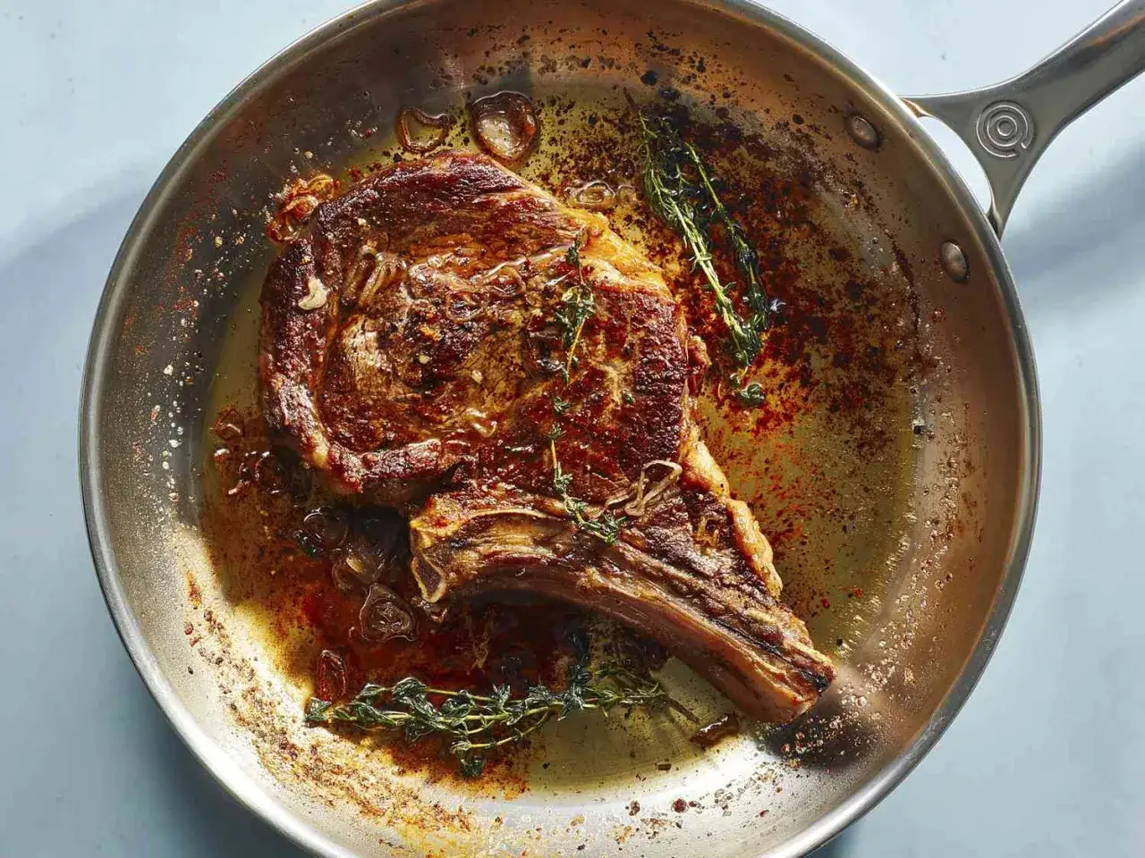 Une succulente entrec&ocirc;te saignante cuit dans une po&ecirc;le avec du thym et des oignons. La viande est dor&eacute;e et juteuse.