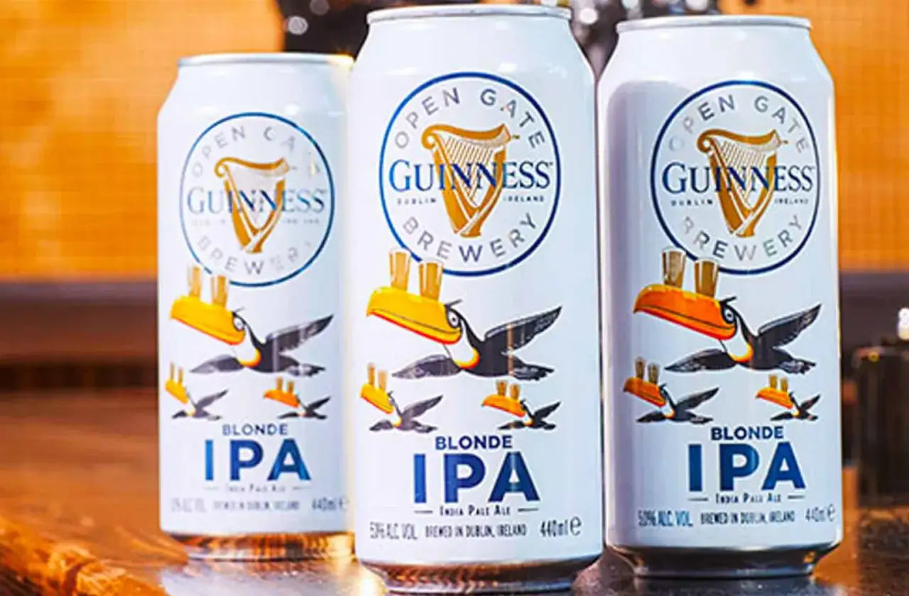 Trois canettes de bière Guinness Blonde IPA, avec des toucans et des oiseaux. Le taux alcool est de 5%.