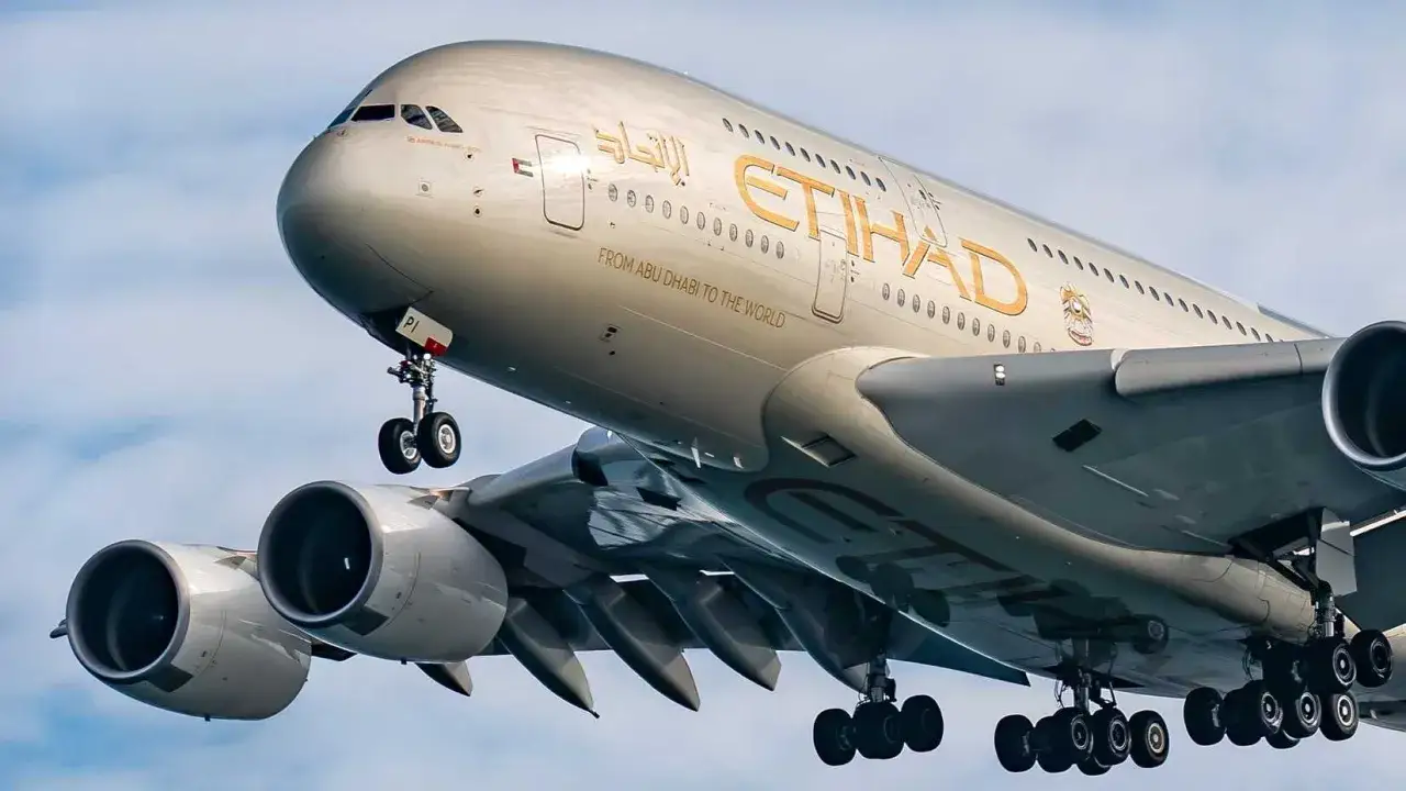 Największy samolot pasażerski, Airbus A380 linii Etihad, z wysuniętym podwoziem, gotowy do lądowania.