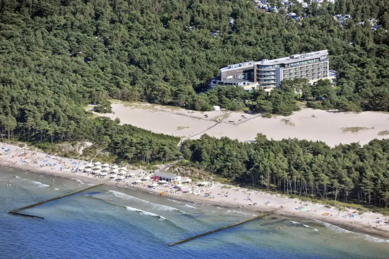 Widok z lotu ptaka na Havet Hotel Resort & Spa otoczony lasem sosnowym, z piaszczystą plażą i turystami.