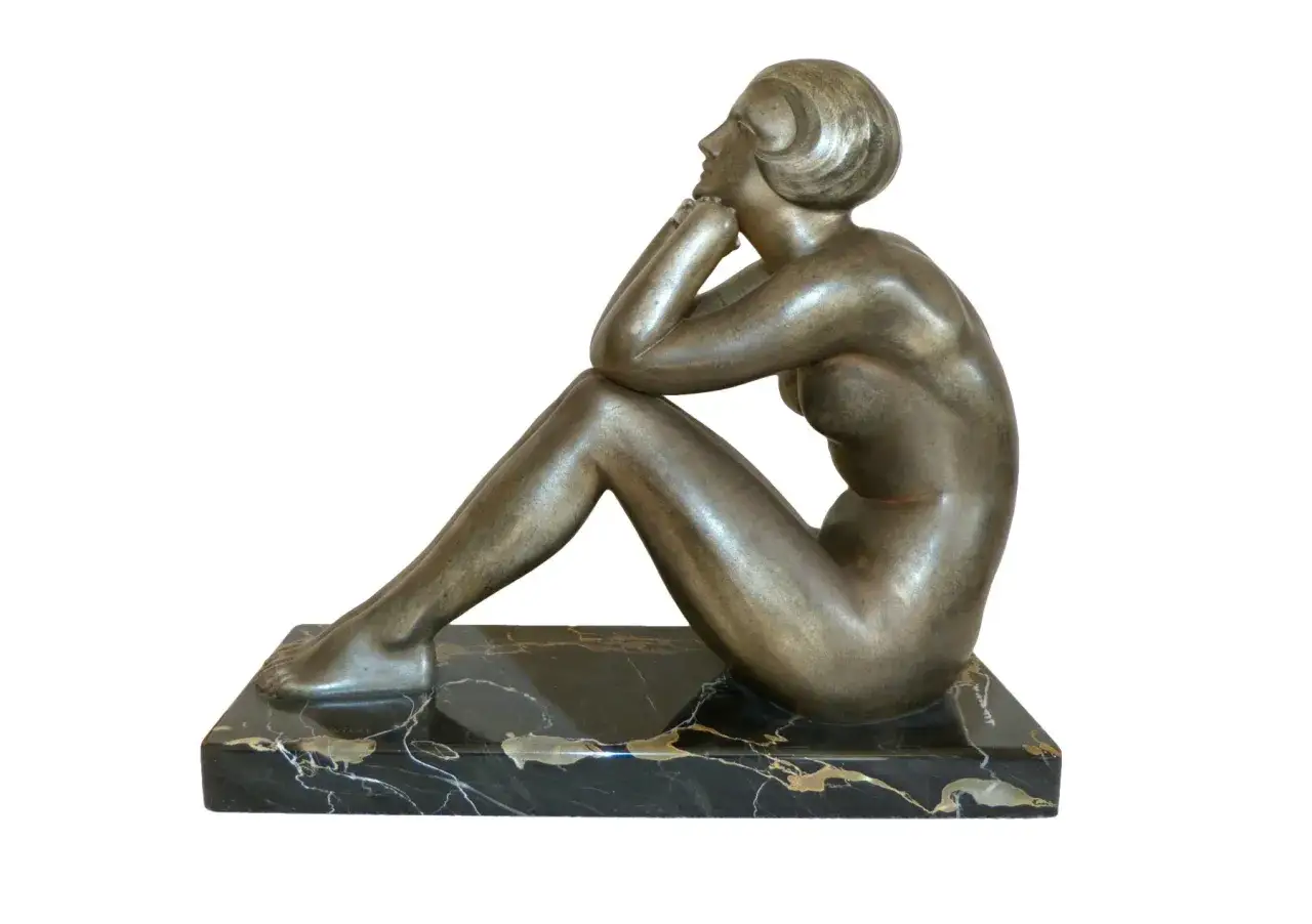 Sculpture art déco d'une femme assise, les mains sous le menton, sur un socle en marbre noir. Une œuvre de Guiraud Riviere.