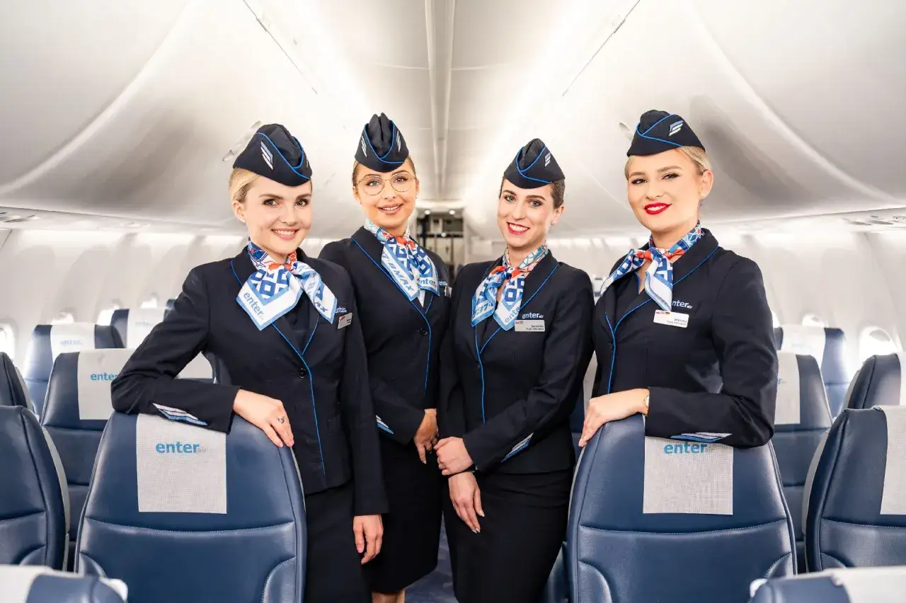 Uśmiechnięte stewardessy Enter Air w granatowych mundurkach. Chcesz wiedzieć, jak sprawdzić numer lotu Enter Air? Zapytaj personel pokładowy!