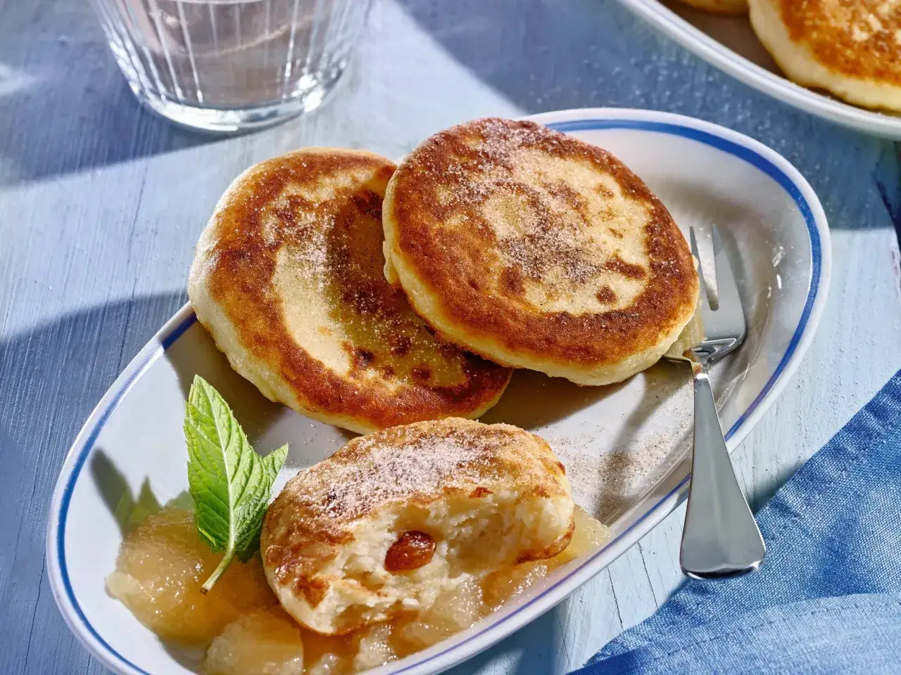 Goldbraune Quarkkeulchen mit Zucker bestreut, serviert mit Apfelmus und Minze. Ein leckeres Quarkkeulchen Rezept zum Genie&szlig;en.