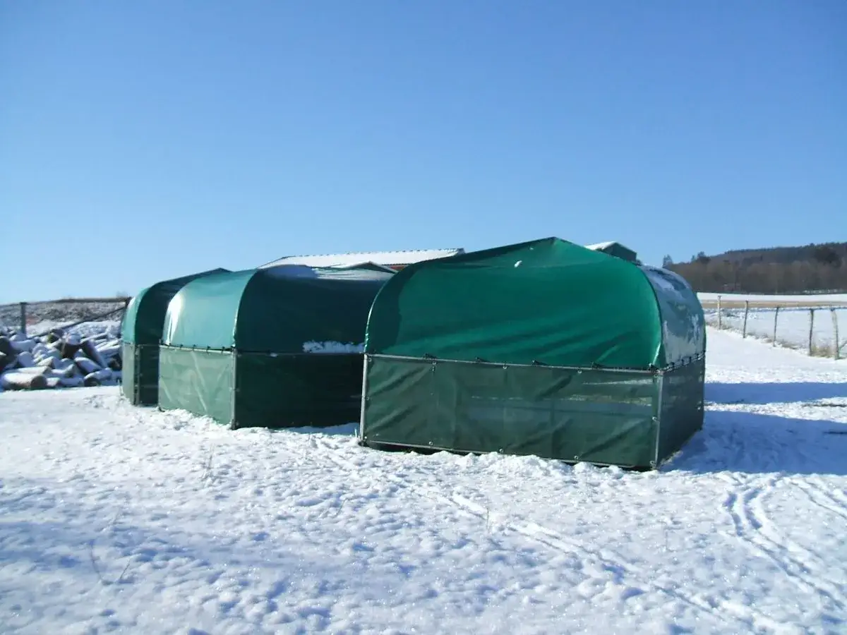 Gr&uuml;ne Unterst&auml;nde im Schnee, bereit f&uuml;r die Ziegen im Winter.