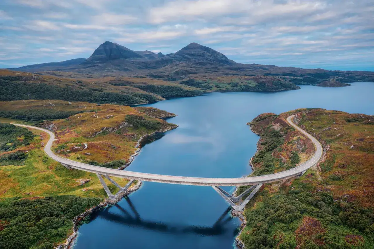 Un puente moderno cruza un fiordo azul en la **ruta 500 Escocia**. Monta&ntilde;as escarpadas y colinas cubiertas de brezo rodean el paisaje.