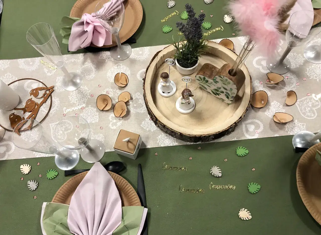 Jolie composition florale pour une communion, avec des figurines, des rondins de bois et des décorations végétales.