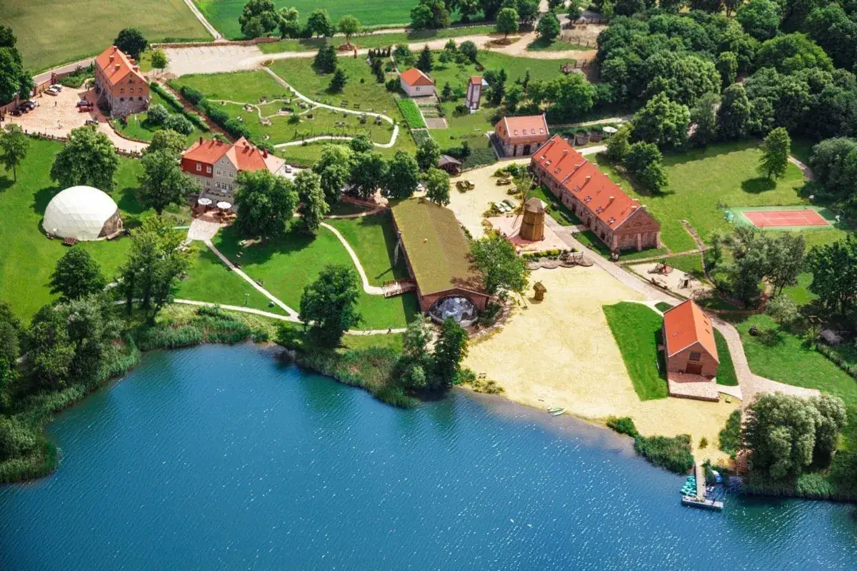 Malowniczy hotel spa Wielkopolska nad jeziorem, z plażą, kortem tenisowym i zielonymi terenami.
