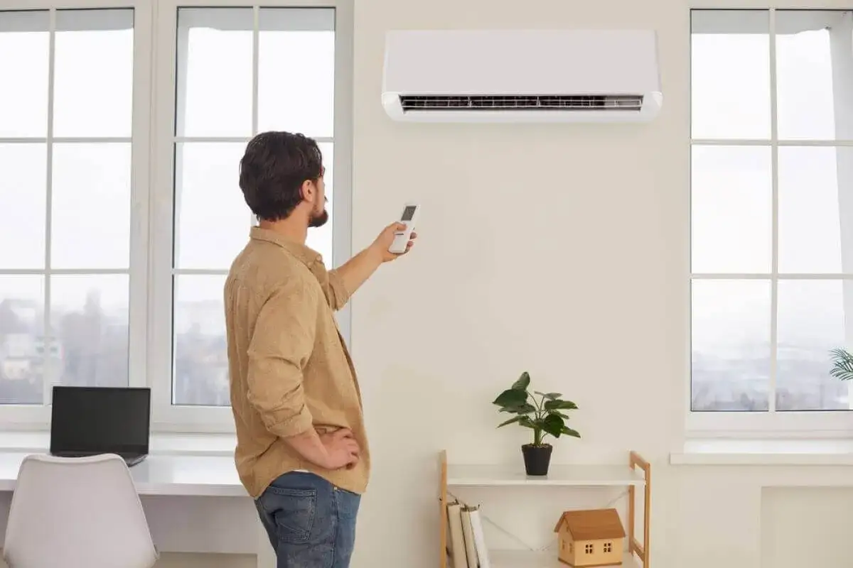 Hombre con control remoto ajustando el aire acondicionado. Listo para cargar gas si es necesario.